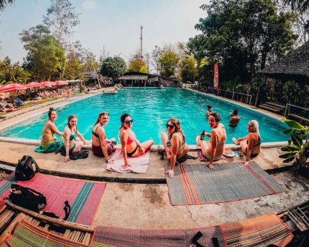 girls in bikinis sat by large pool in Thailand